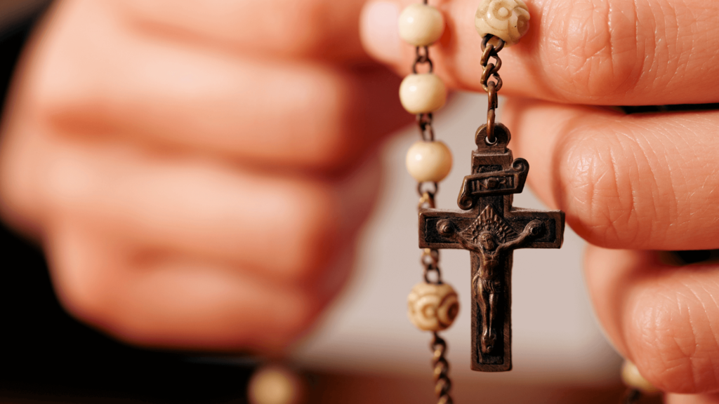 Close-up of a hand holding a rosary with a crucifix.