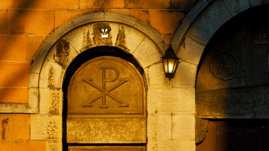 Chi-Rho symbol carved on a stone archway with lanterns.

