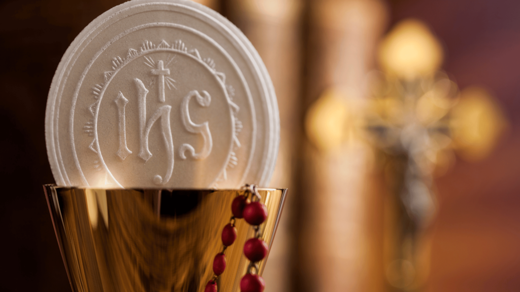 Eucharistic host with the IHS symbol in a gold chalice.

