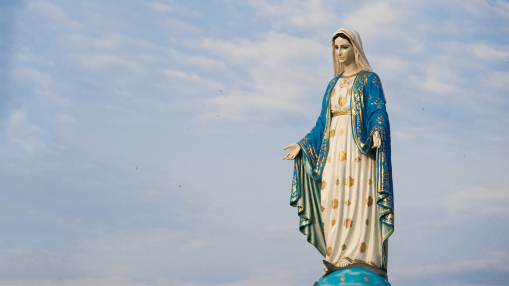 Majestic statue of the Virgin Mary standing against a serene blue sky. This image captures the grace and divine presence of Mary, symbolizing her purity and devotion.